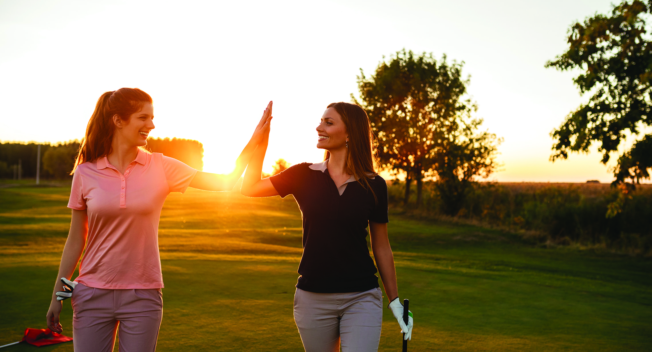 Shot of two female golfers giving high five on the golf course